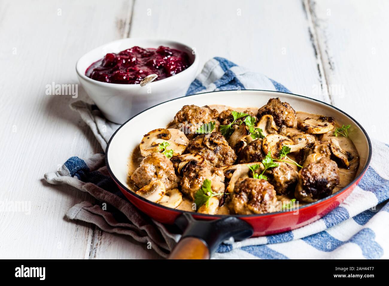 Frying pan with Swedish kottbullar meatballs in mushroom gravy and bowl of mashed cranberries Stock Photo
