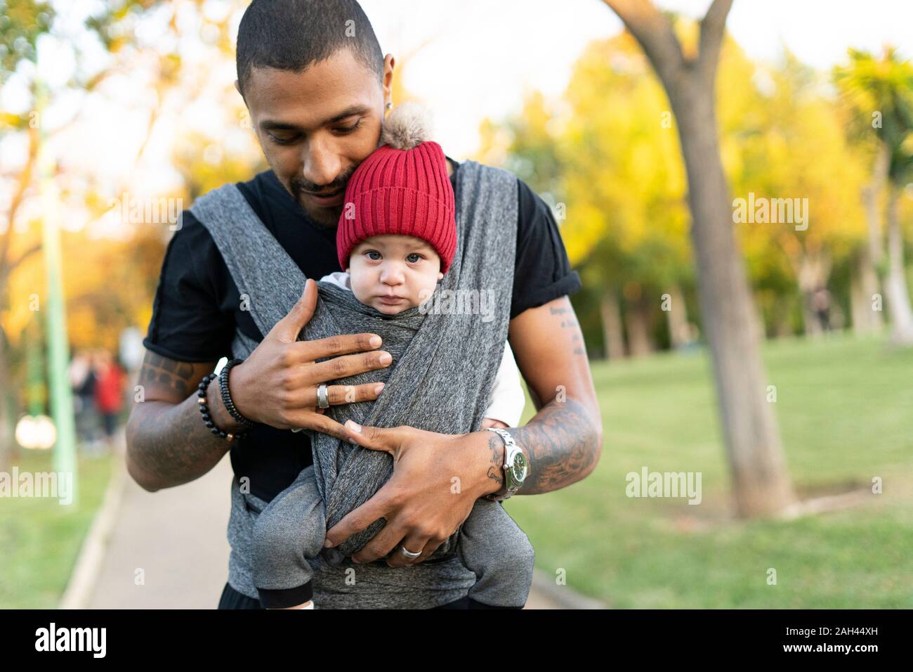Young father carrying baby son in a baby sling Stock Photo