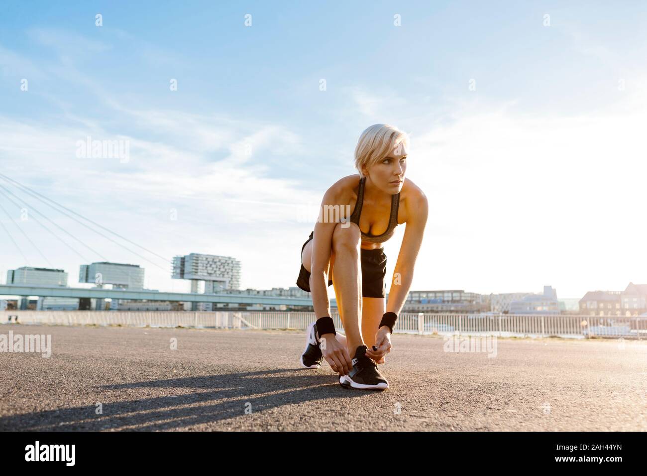 Blonde woman jogging, tying shoes Stock Photo