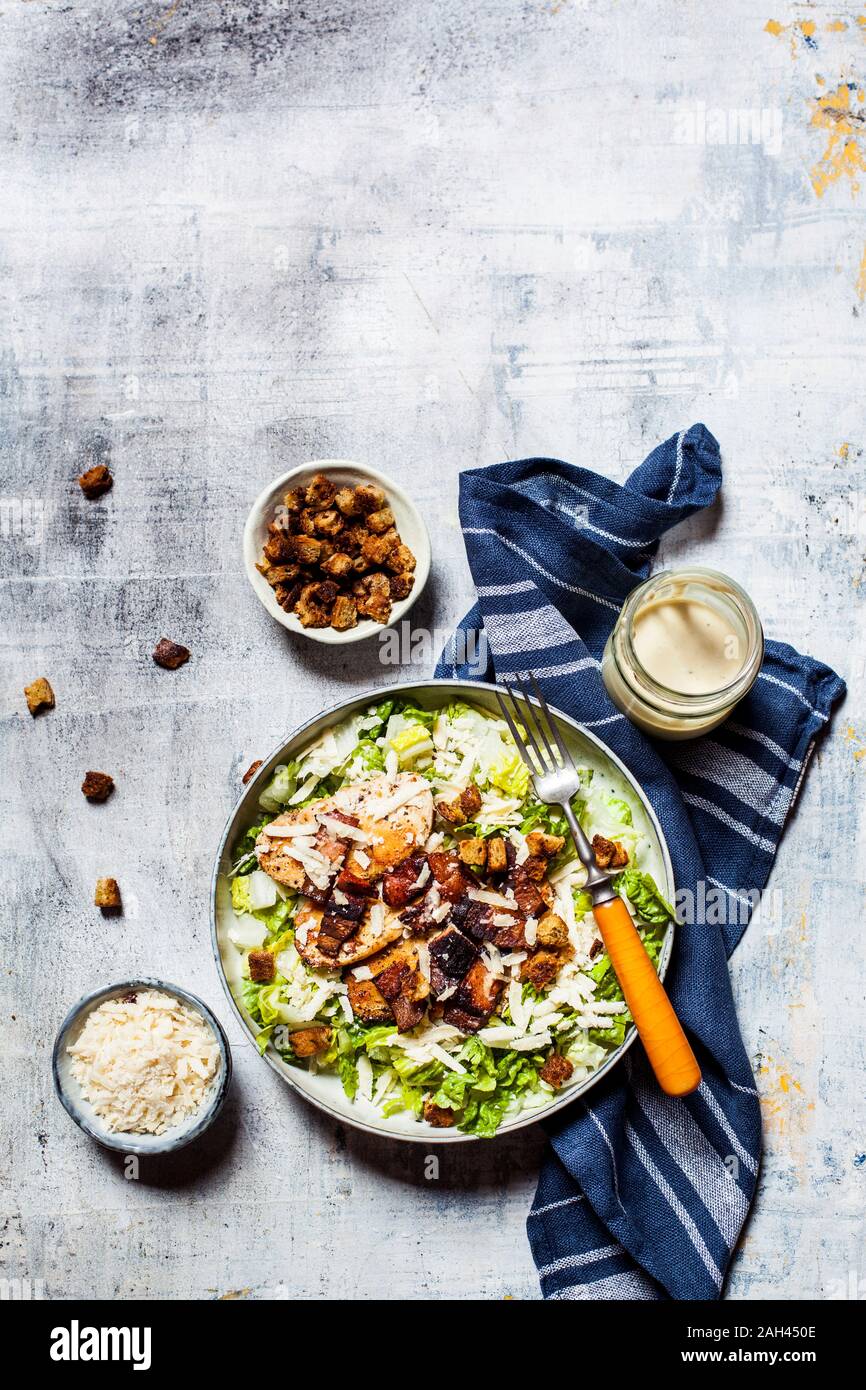 Bowl of Caesar salad with romaine lettuce, Parmesan cheese, bacon, chicken breast and croutons Stock Photo