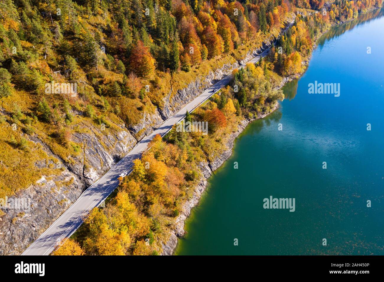 Germany, Bavaria, Lenggries, Aerial view of empty highway stretching along shore of Sylvenstein Reservoir in autumn Stock Photo