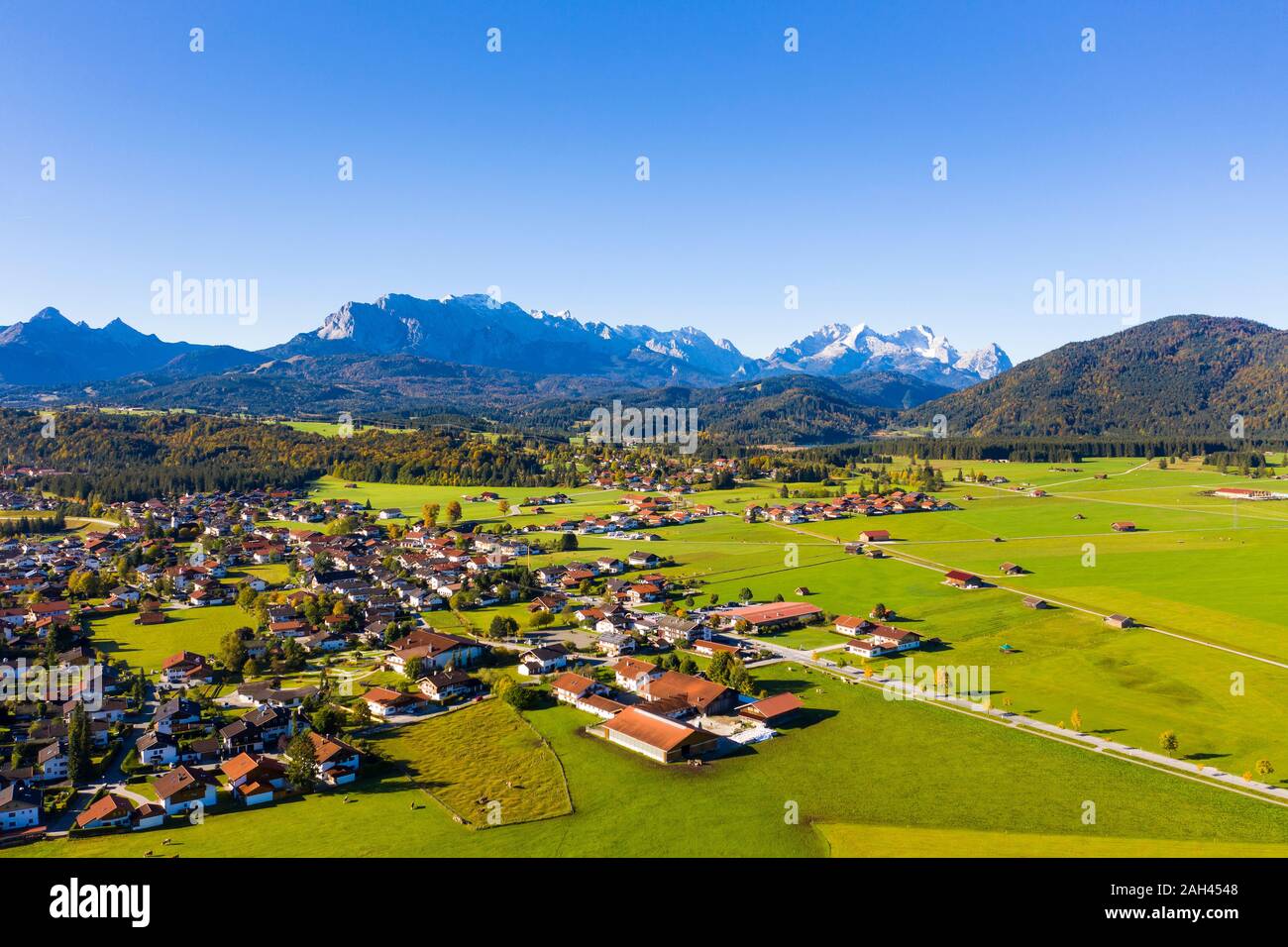Germany, Bavaria, Upper Bavaria, Werdenfelser Land, Krun, Aerial view of green fields and village with Wetterstein Mountains in background Stock Photo
