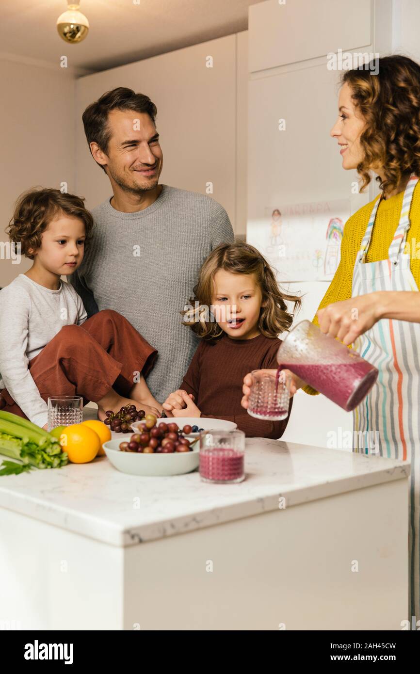 Mother preparing a smoothie for her family in kitchen Stock Photo