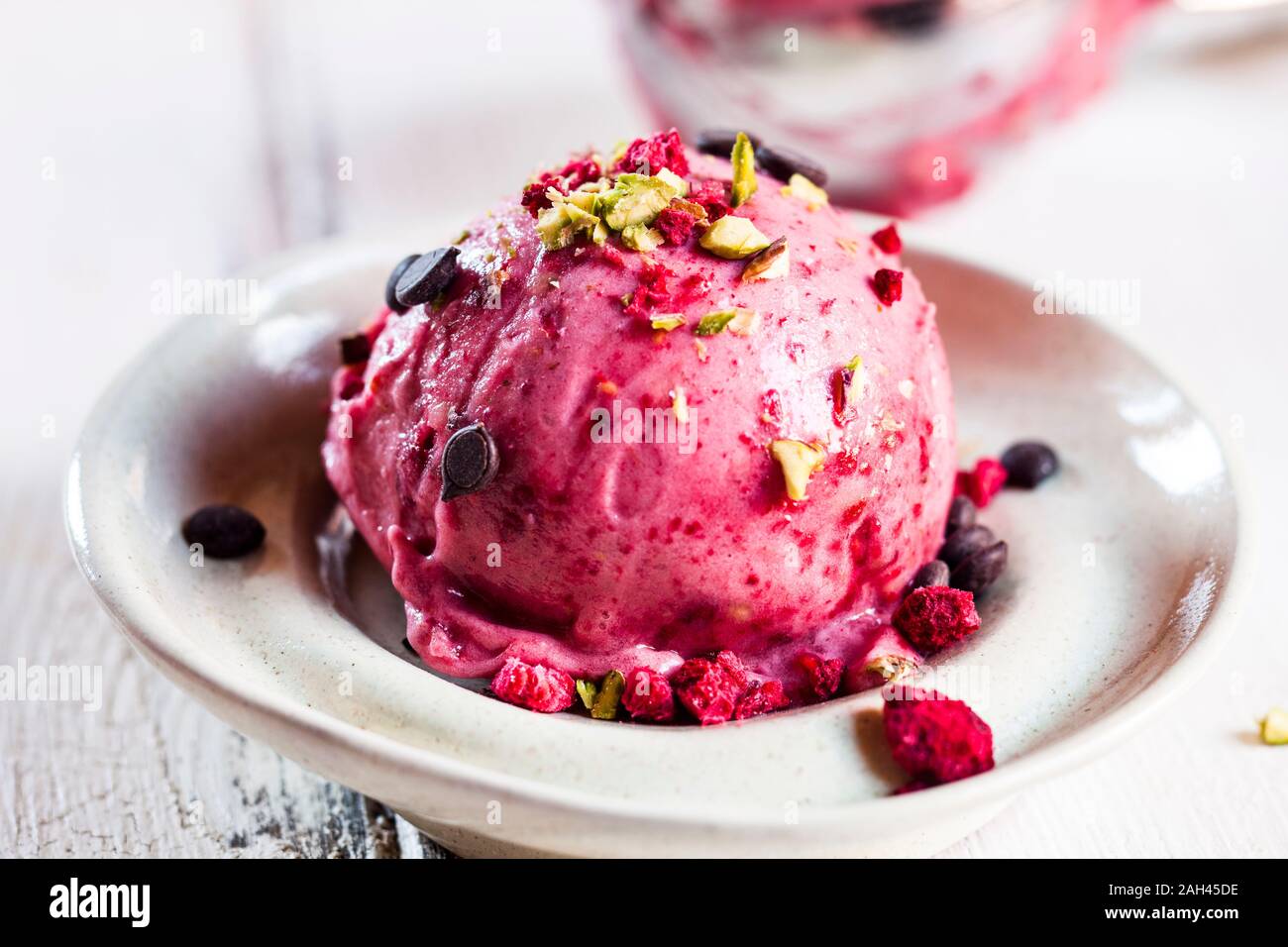 Plate of vegan sugarfree nice cream with raspberries, bananas, sprinkled pistachios and chocolate Stock Photo