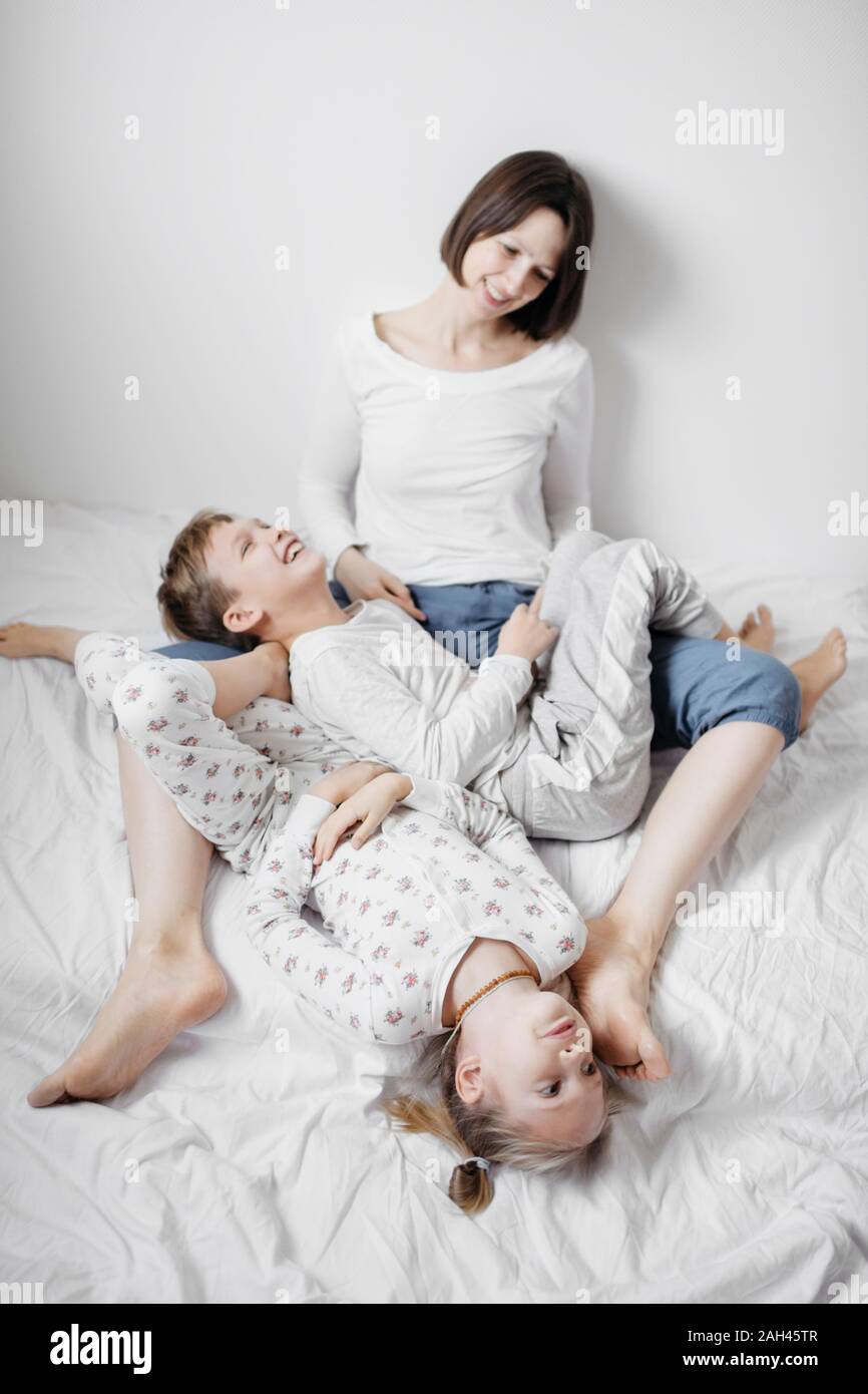 Mother having fun time with two kids on bed Stock Photo