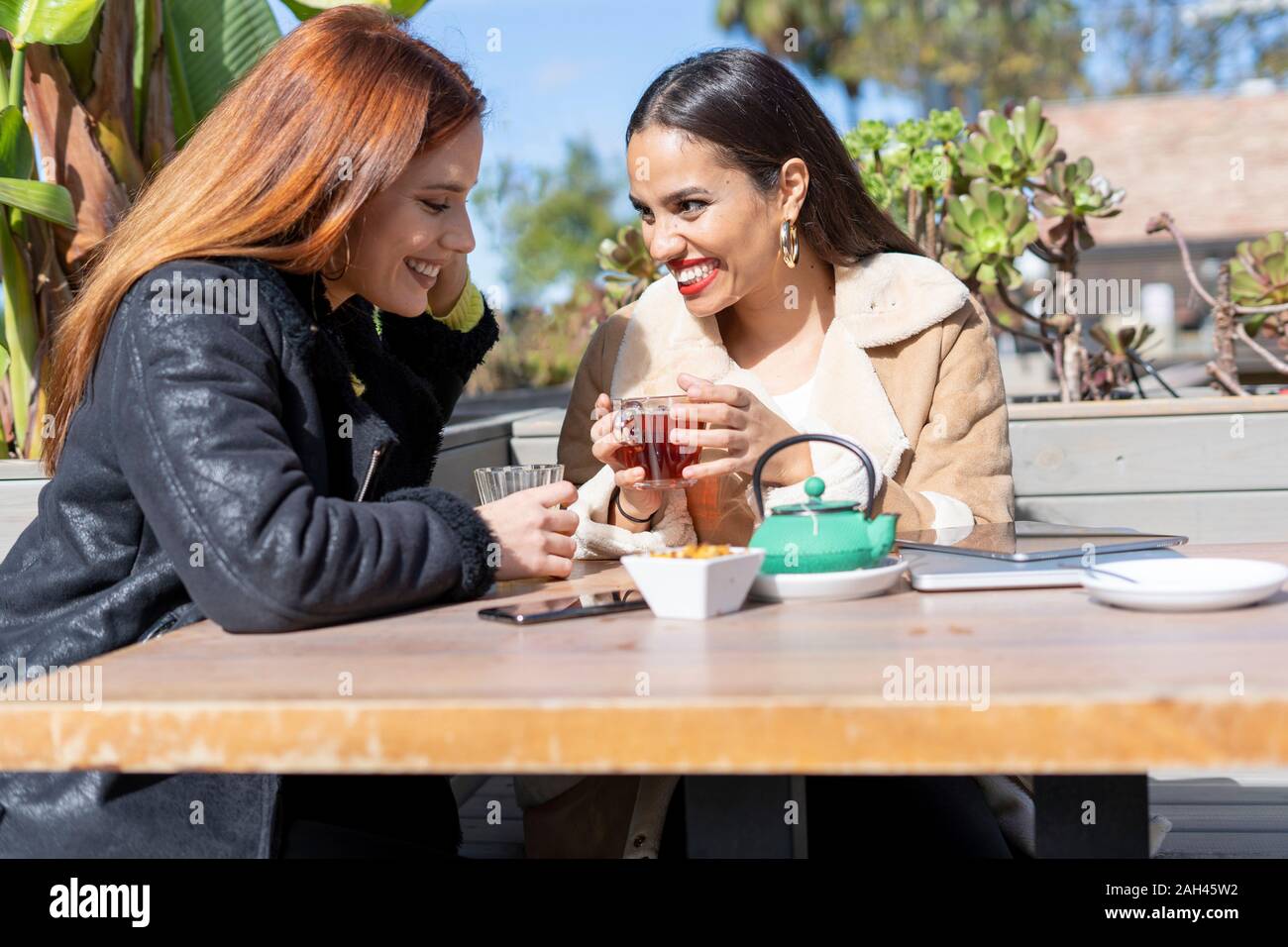 Two female friends drinking tea outdoors at a coffee shop Stock Photo ...
