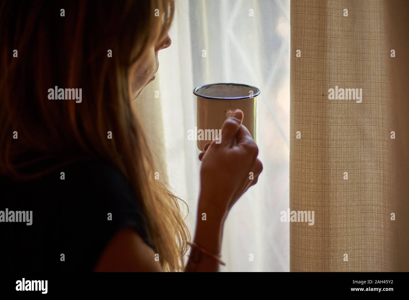 Woman having a cup of coffee in front of the window Stock Photo