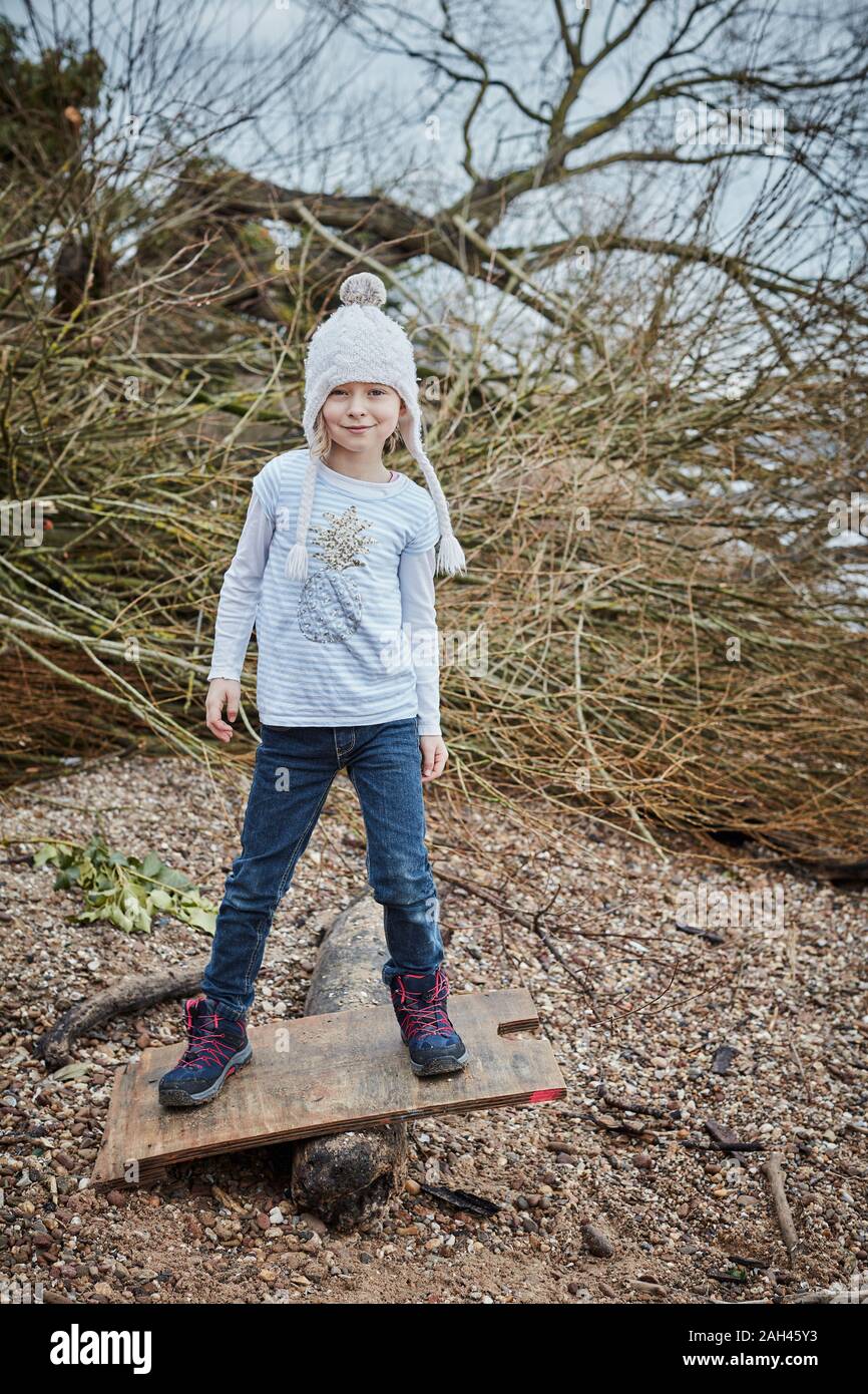 Portrait of smiling little girl wearing bobble hat balancing on seesaw Stock Photo