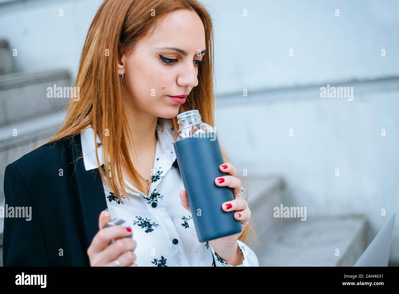 Young businesswoman rinking from reusable bottle outdoors Stock Photo