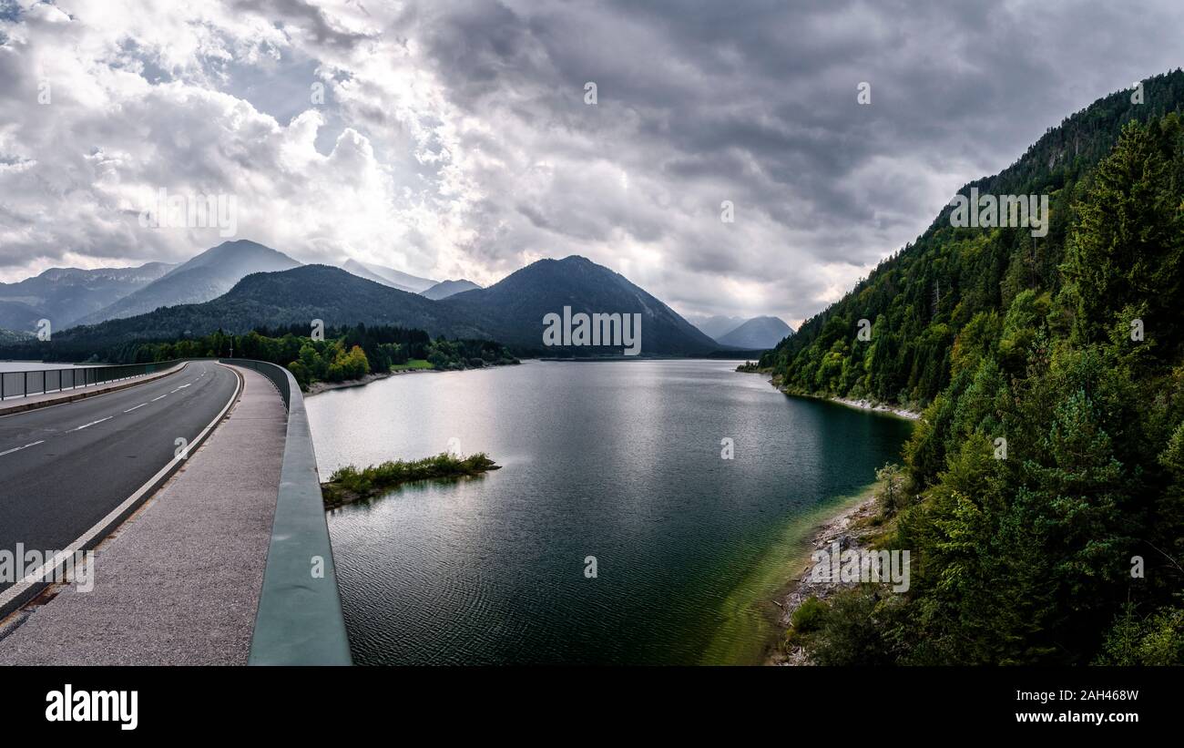 Germany, Bavaria, Cloudy sky over highway crossing Sylvenstein Reservoir Stock Photo