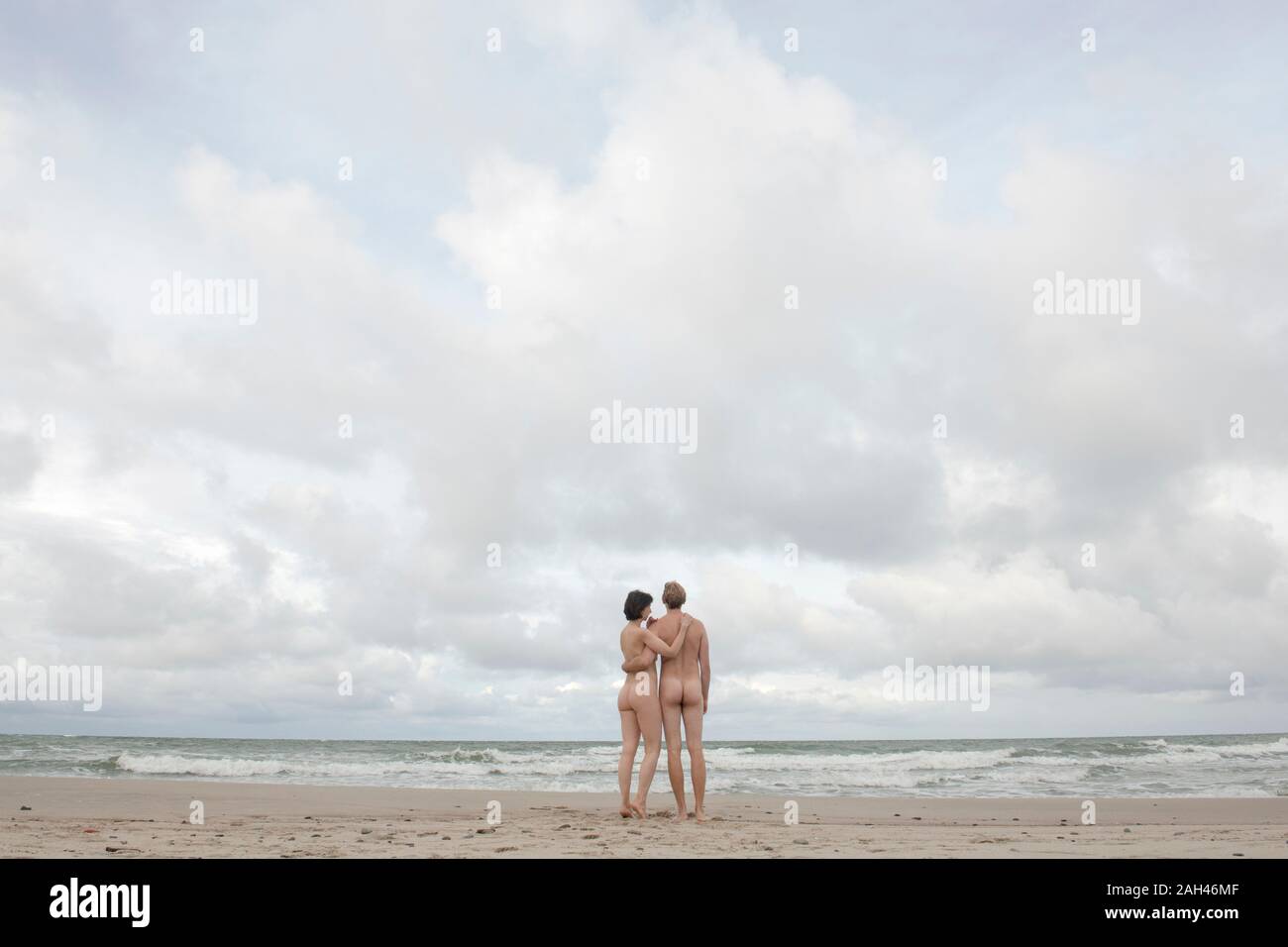 Nude couple standing on the beach, embracing Stock Photo