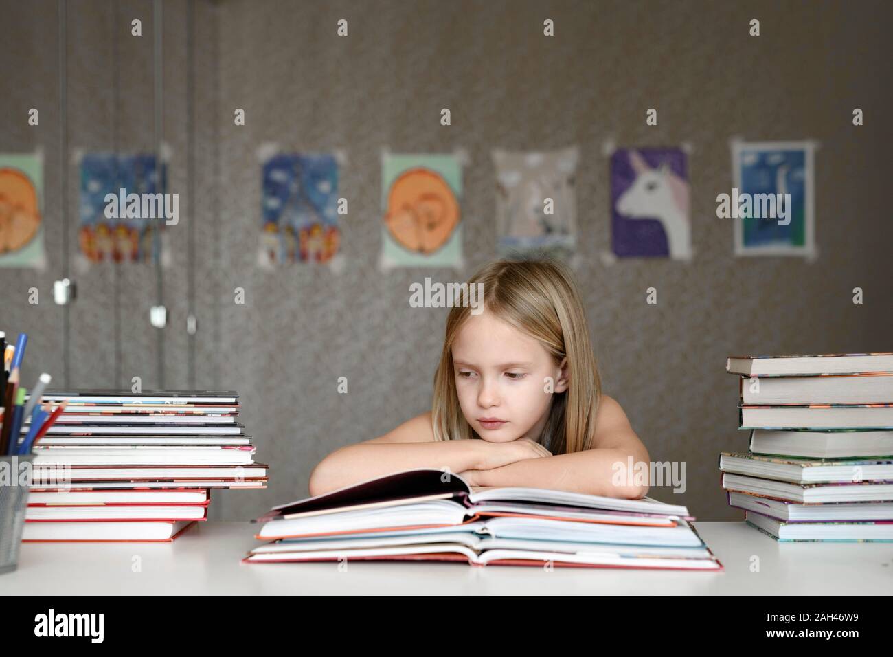 Girl sitting at table at home reading books Stock Photo