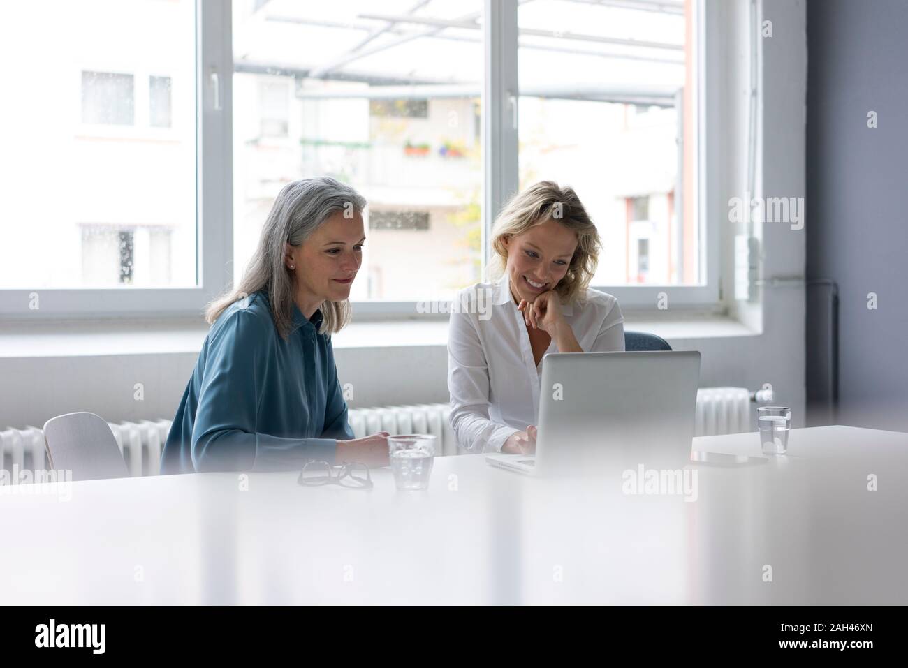 Two businesswomen using laptop at desk in office together Stock Photo