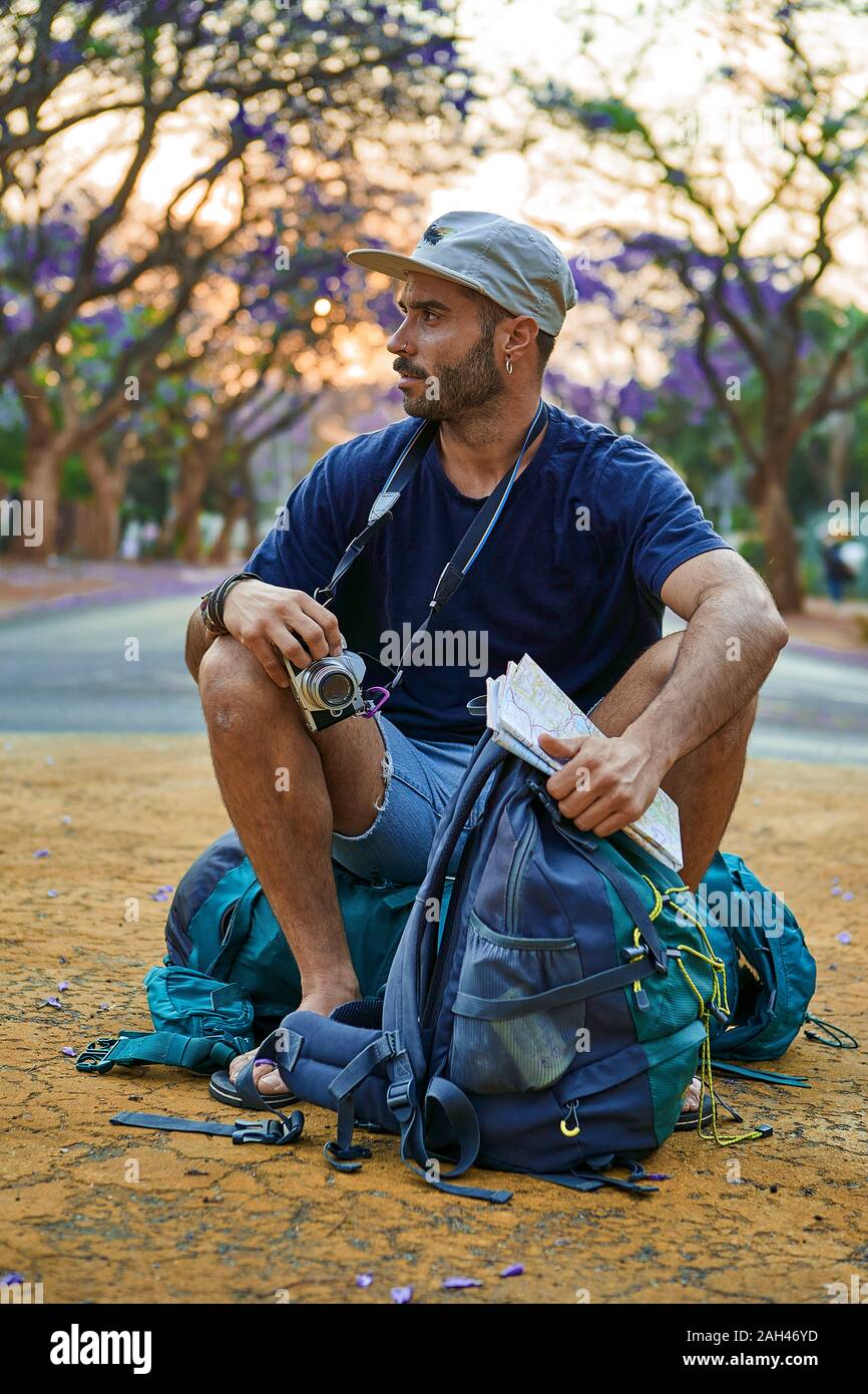 Backpacker sitting on his bag in the middle of a street Stock Photo