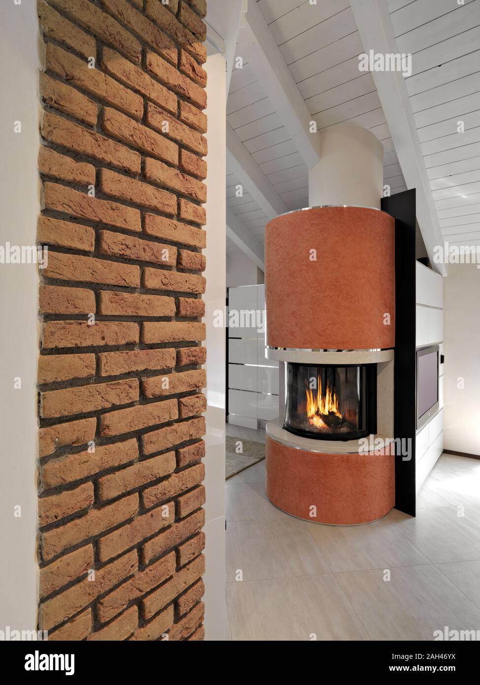 interior shot of a modern apartment in the attic room in foreground the modern fireplace Stock Photo
