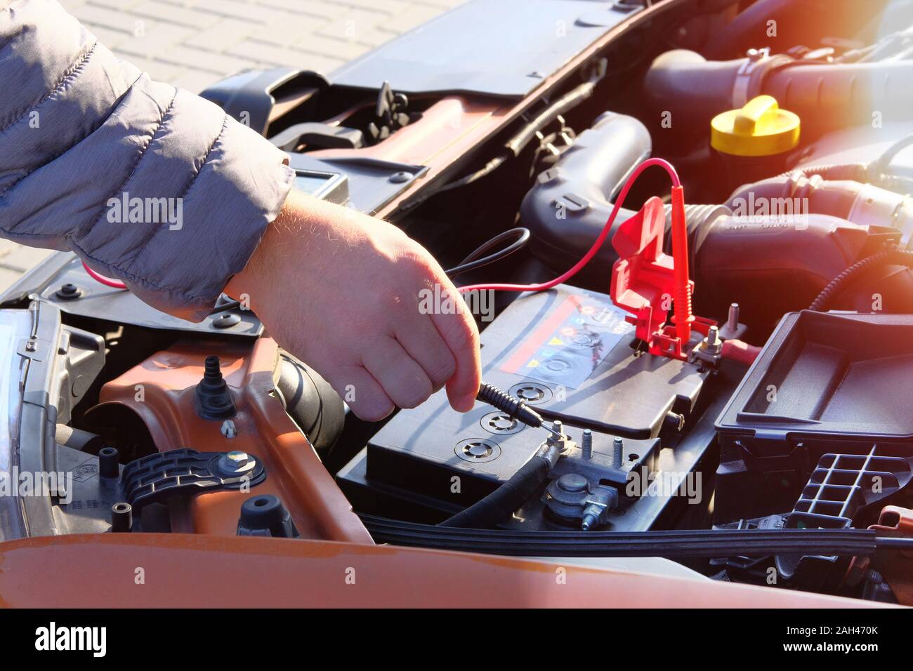 Measurement of battery voltage in a car. Car mechanic is using a multimeter with voltage range measurement. Stock Photo