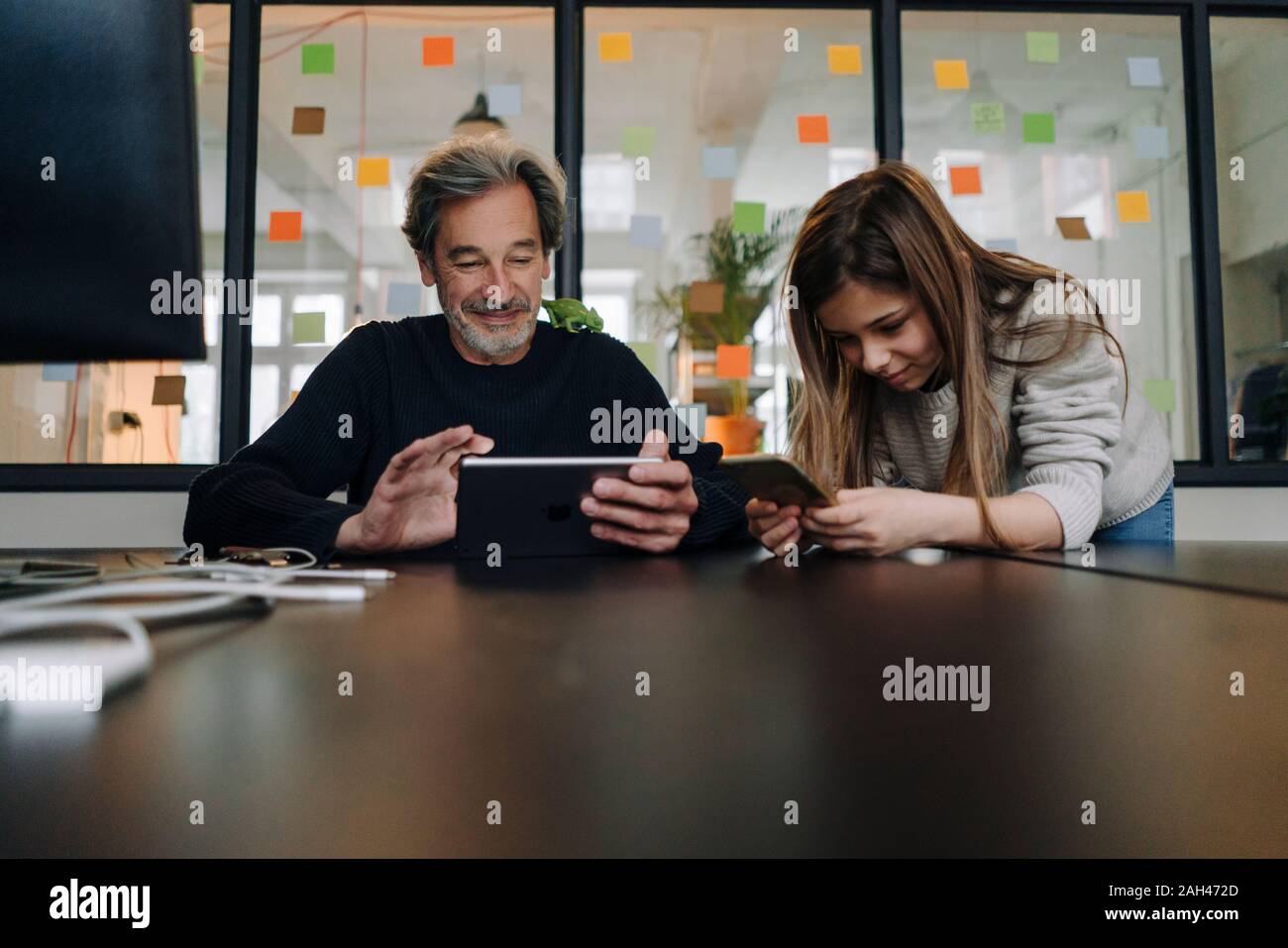 Casual senior buisinessman and girl using tablet and smartphone in office Stock Photo