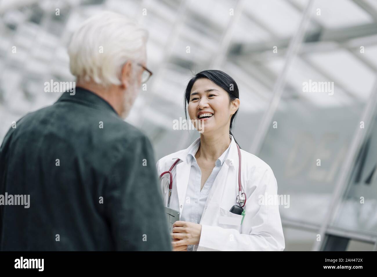 Happy female doctor talking to senior man Stock Photo