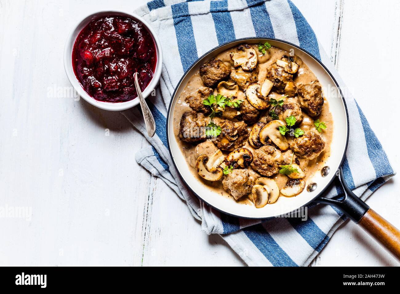 Frying pan with Swedish kottbullar meatballs in mushroom gravy and bowl of mashed cranberries Stock Photo