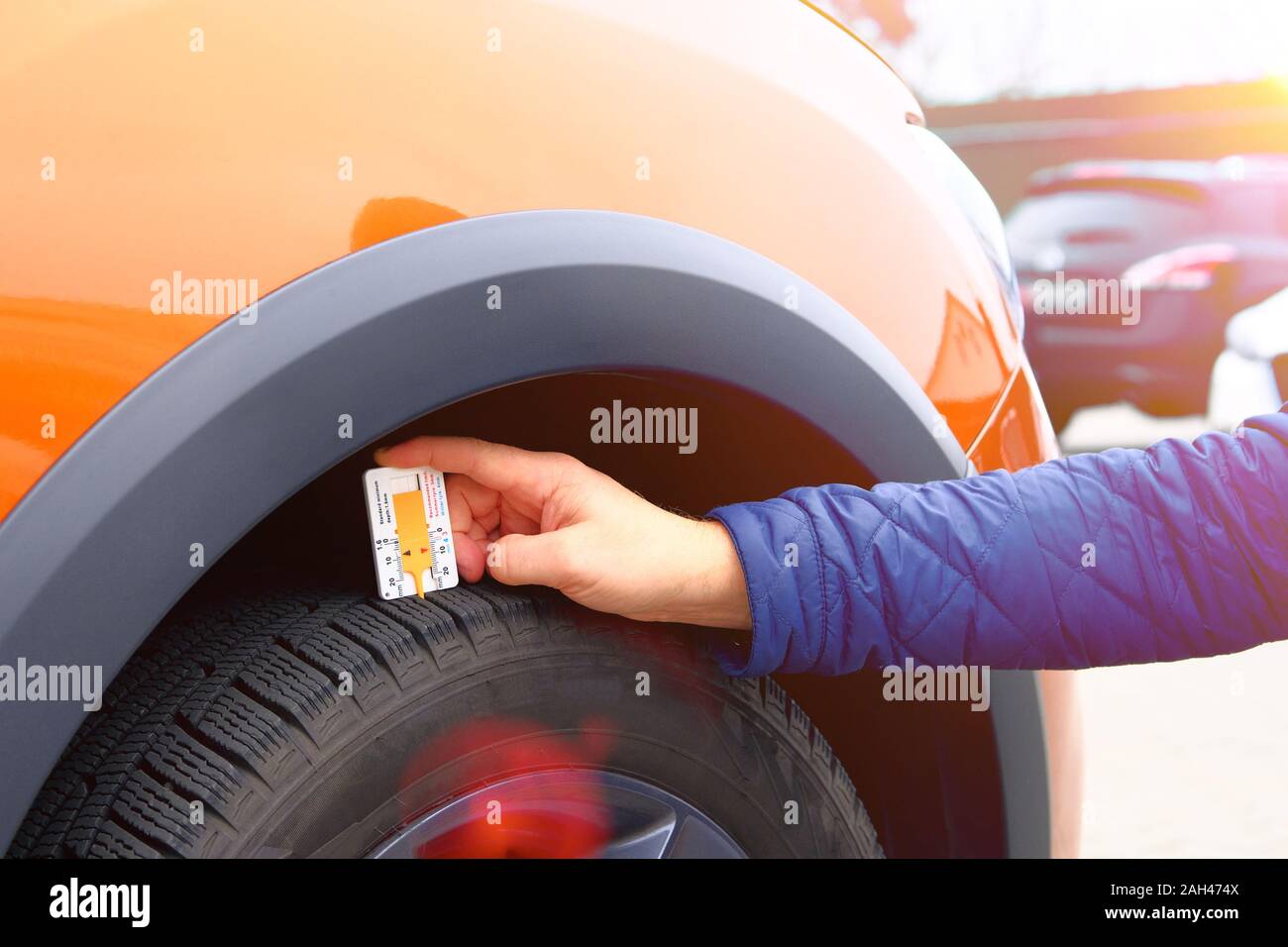 Technician examining the car tire grip with a measuring instrument in service station. Mechanic measures with profiler tread depth. Stock Photo