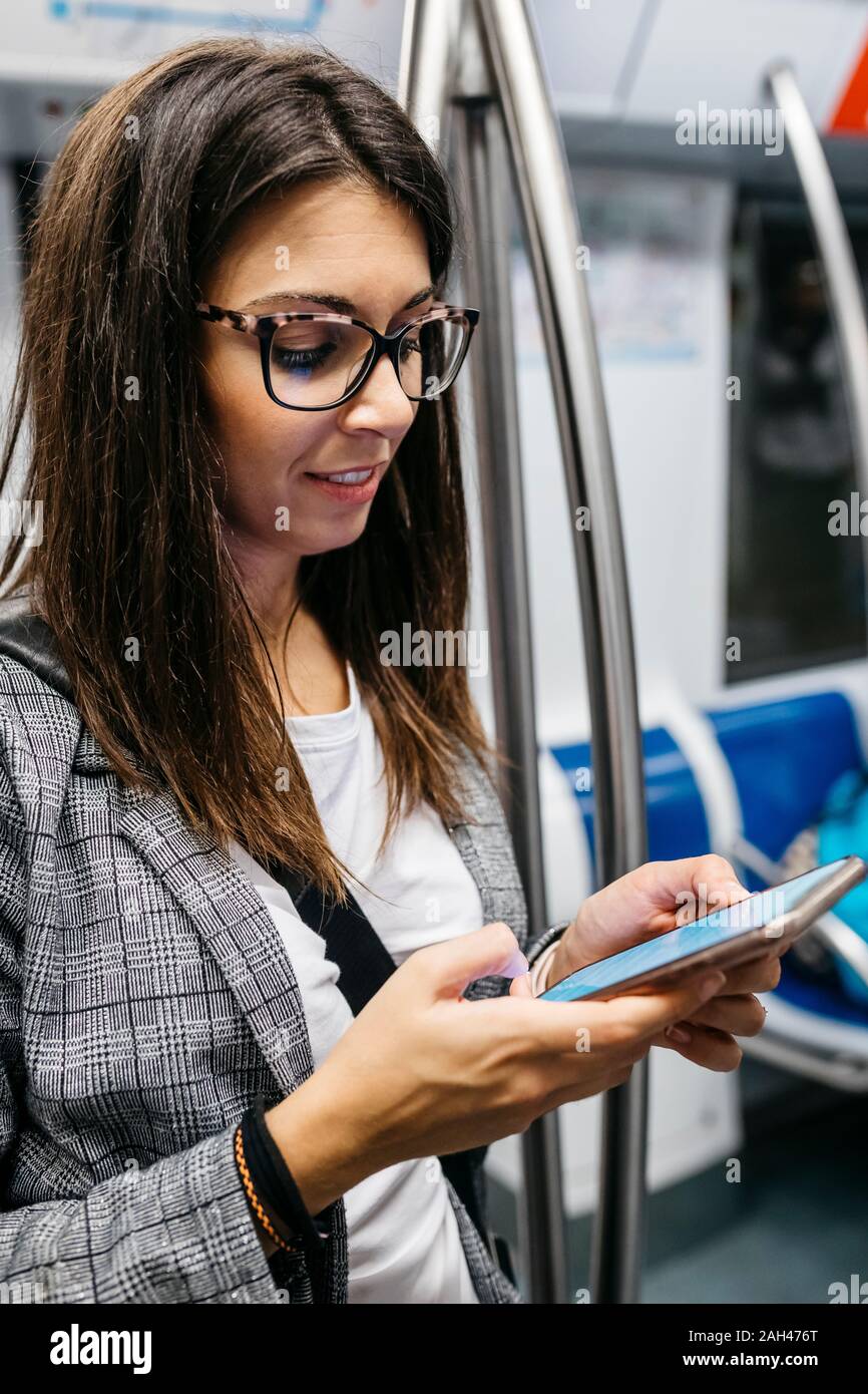 Brunette woman in the subway using the phone while traveling to work Stock Photo