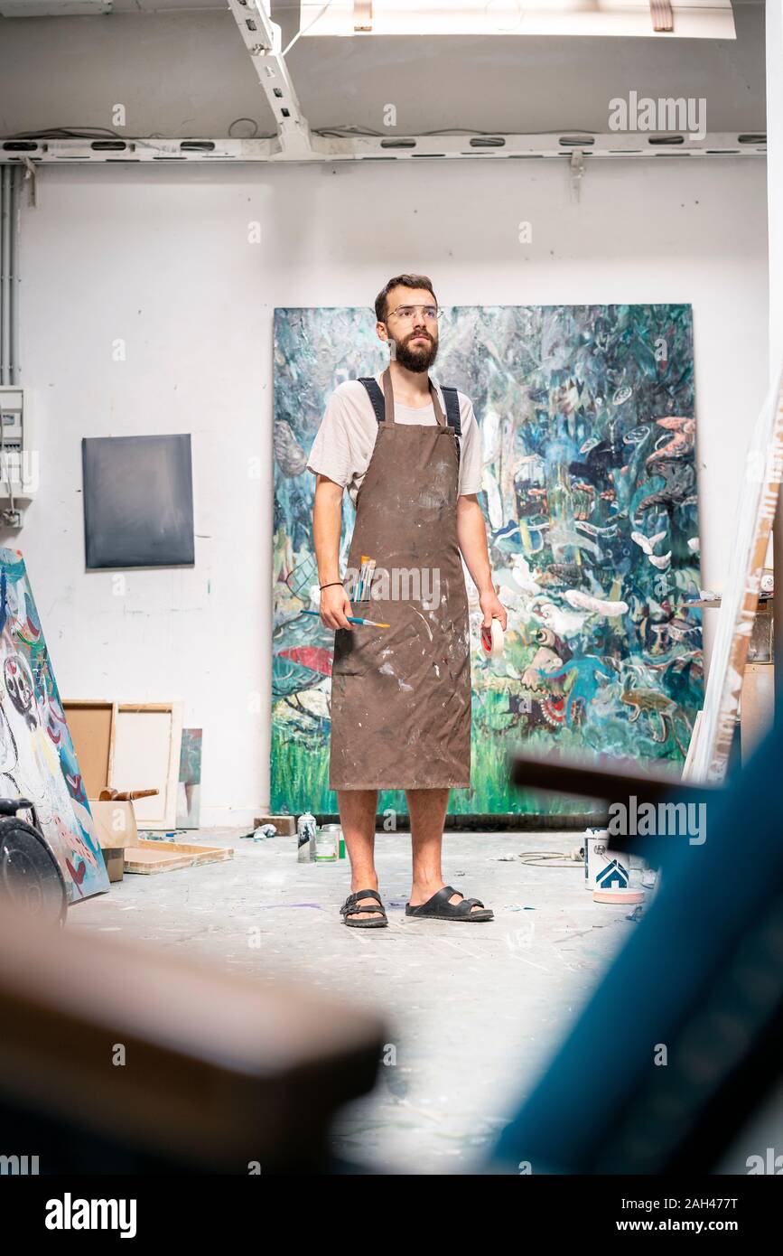 Artist standing in his studio, holding paint brush Stock Photo