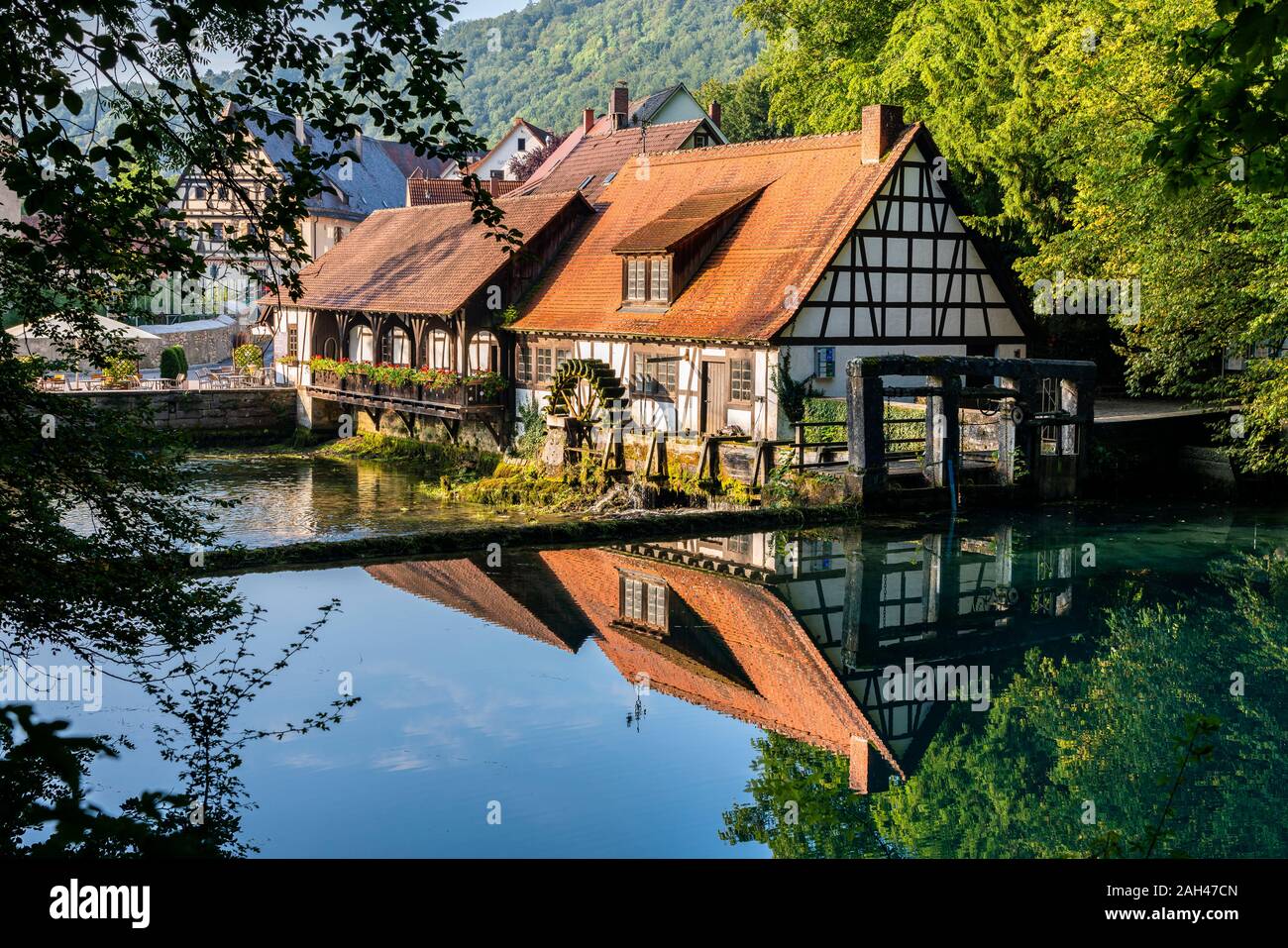 Germany, Baden-Wurttemberg, Blaubeuren, Countryside cottages reflecting in shiny river Stock Photo