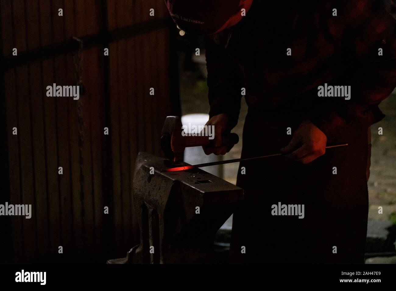 Blacksmith working on metal on anvil at forge Stock Photo