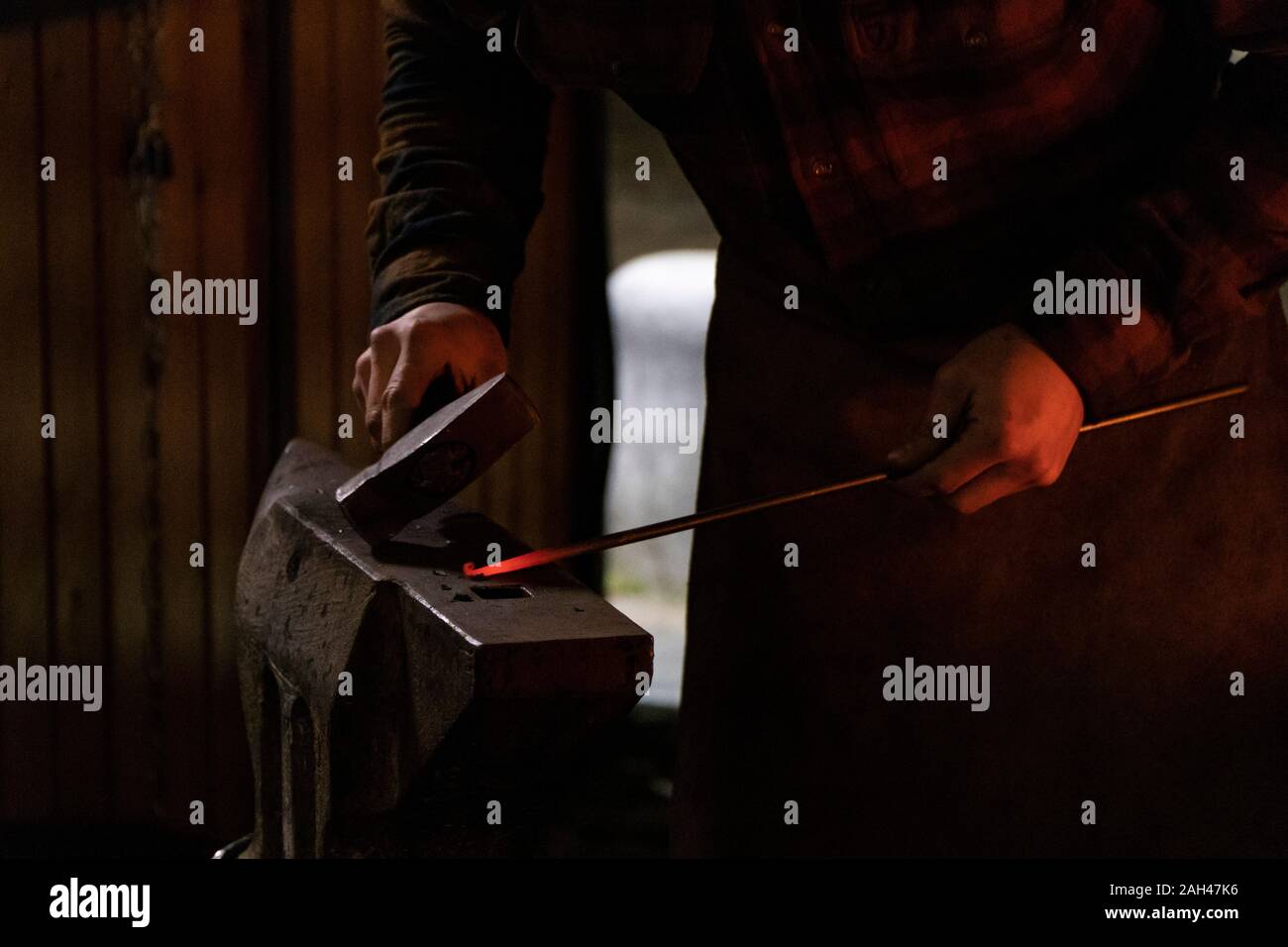 Blacksmith working on metal on anvil at forge Stock Photo