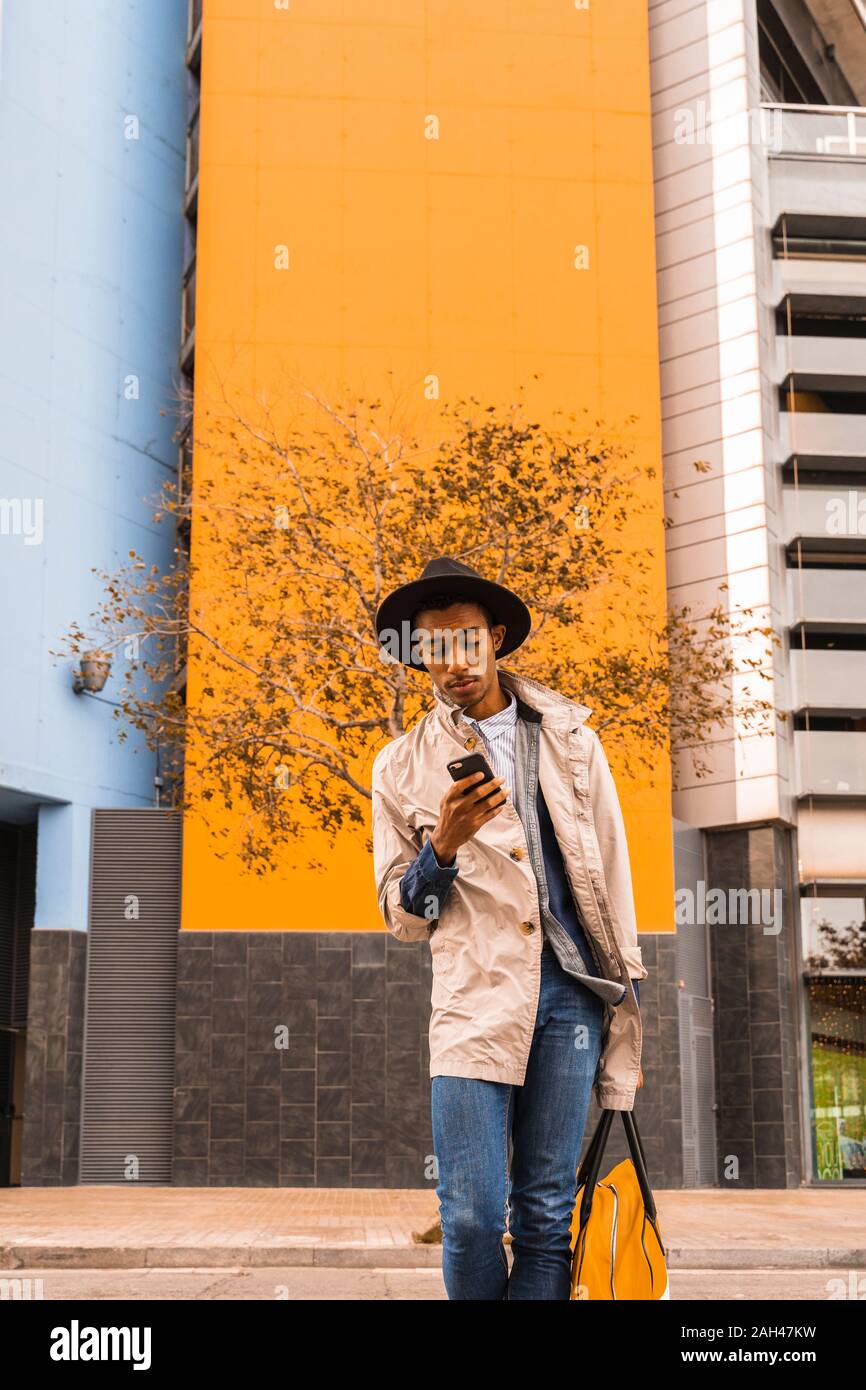 Fashionable young man using smartphone outdoors Stock Photo