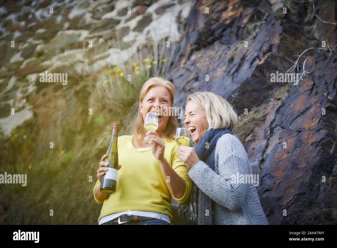 Two laughing mature women drinking wine outdoors Stock Photo