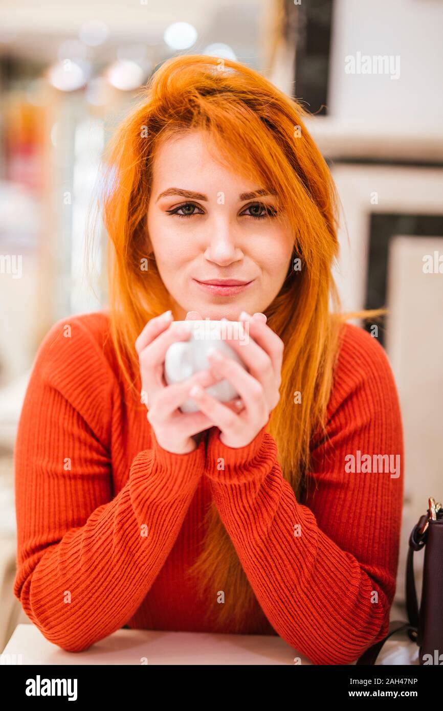 Portrait Of Smiling Young Woman With Orange Dyed Hair Drinking Cup