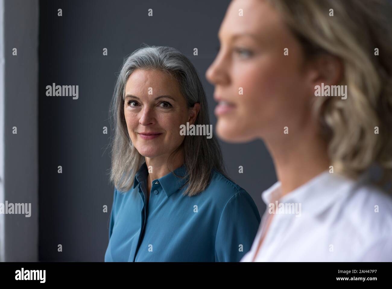 Portrait of confident mature businesswoman with young businesswoman in foreground Stock Photo