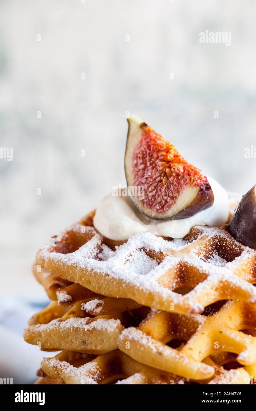 Stack of thick Belgian waffles with whipped cream, powdered sugar and figs Stock Photo