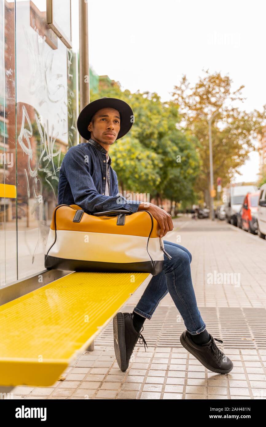 Young man wearing a hat and carrying a bag outdoors Stock Photo