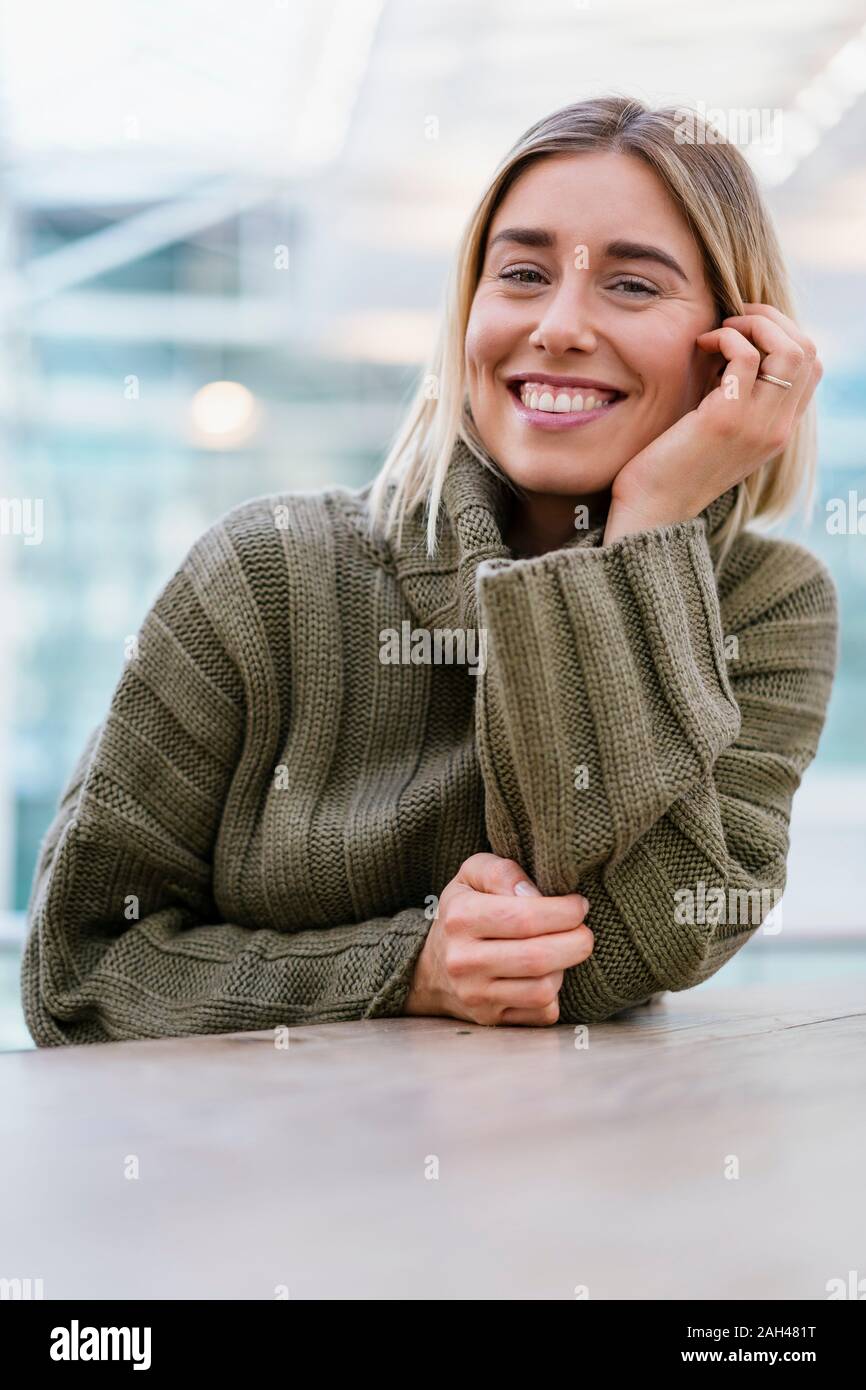 Portrait of a smiling young woman leaning on table Stock Photo