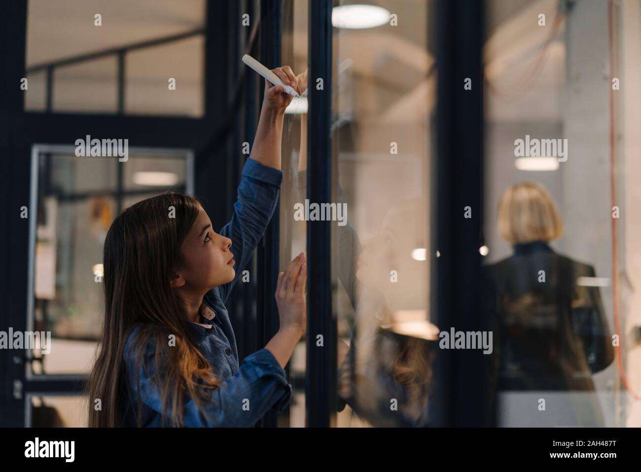 Girl drawing on glass pane in office Stock Photo