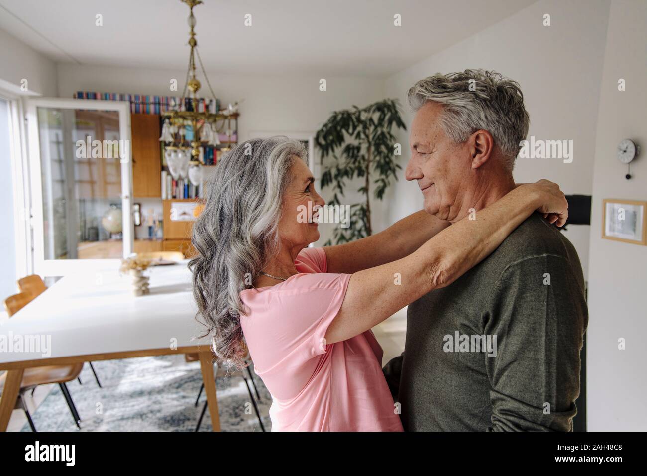 Happy senior couple embracing in living room at home Stock Photo