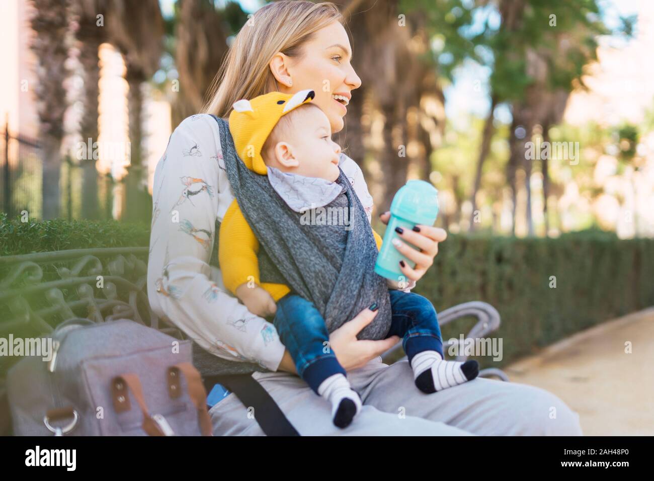 Happy mother resting with baby boy on a park bench Stock Photo - Alamy
