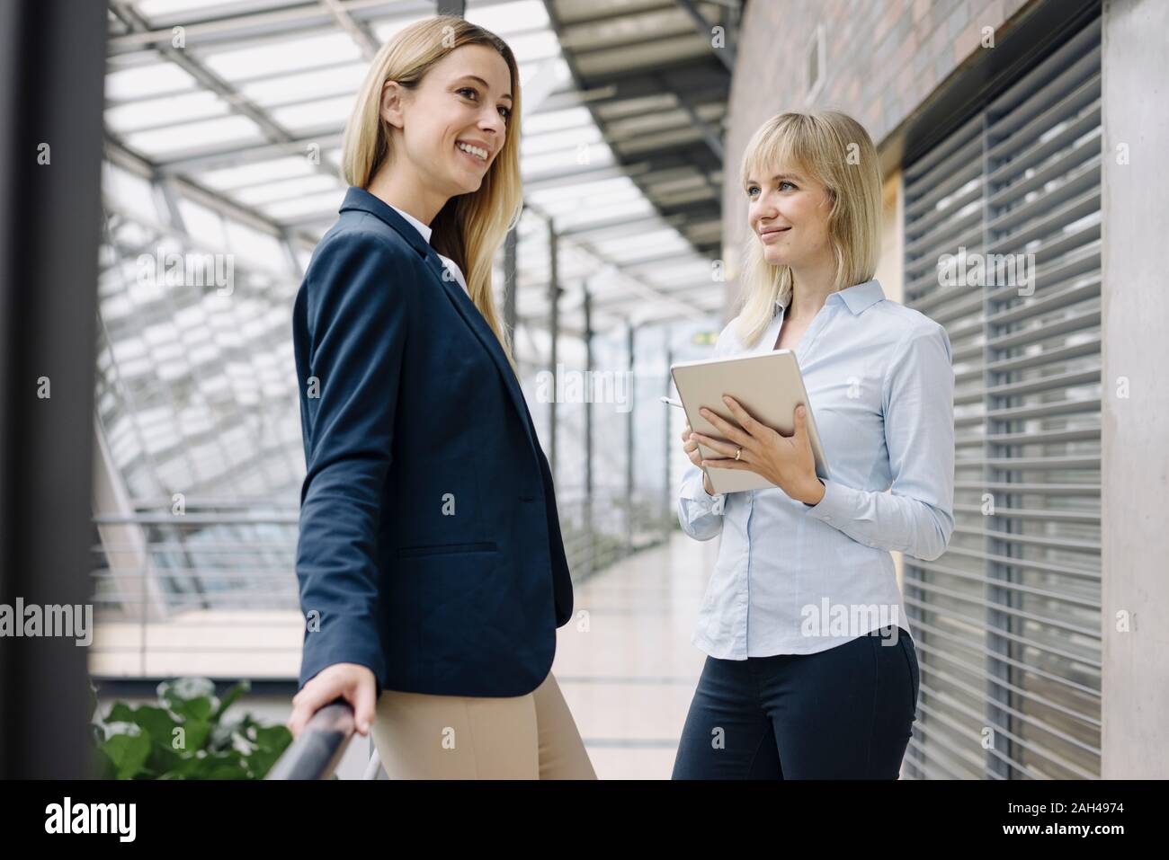 Two happy young businesswomen with tablet in modern office building Stock Photo