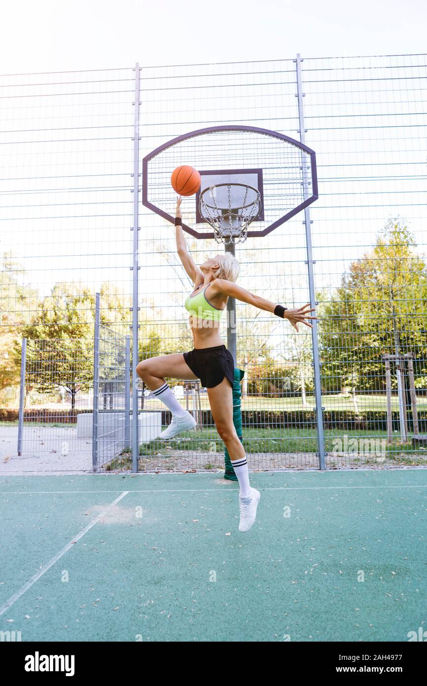 Blonde woman playing basketball, dunking Stock Photo