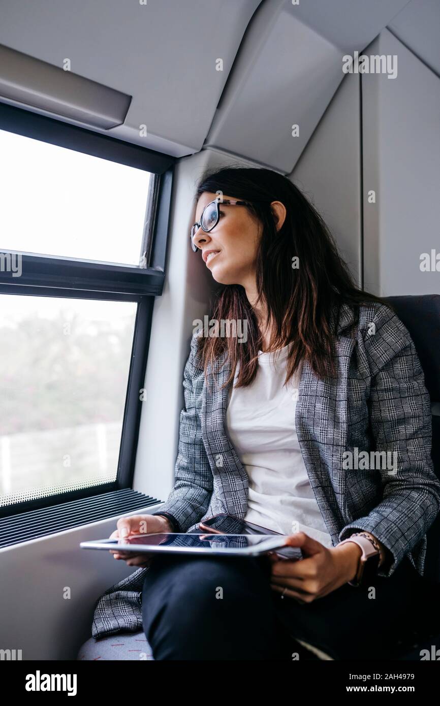 Brunette woman while traveling by train to work, with a tablet in her hands Stock Photo