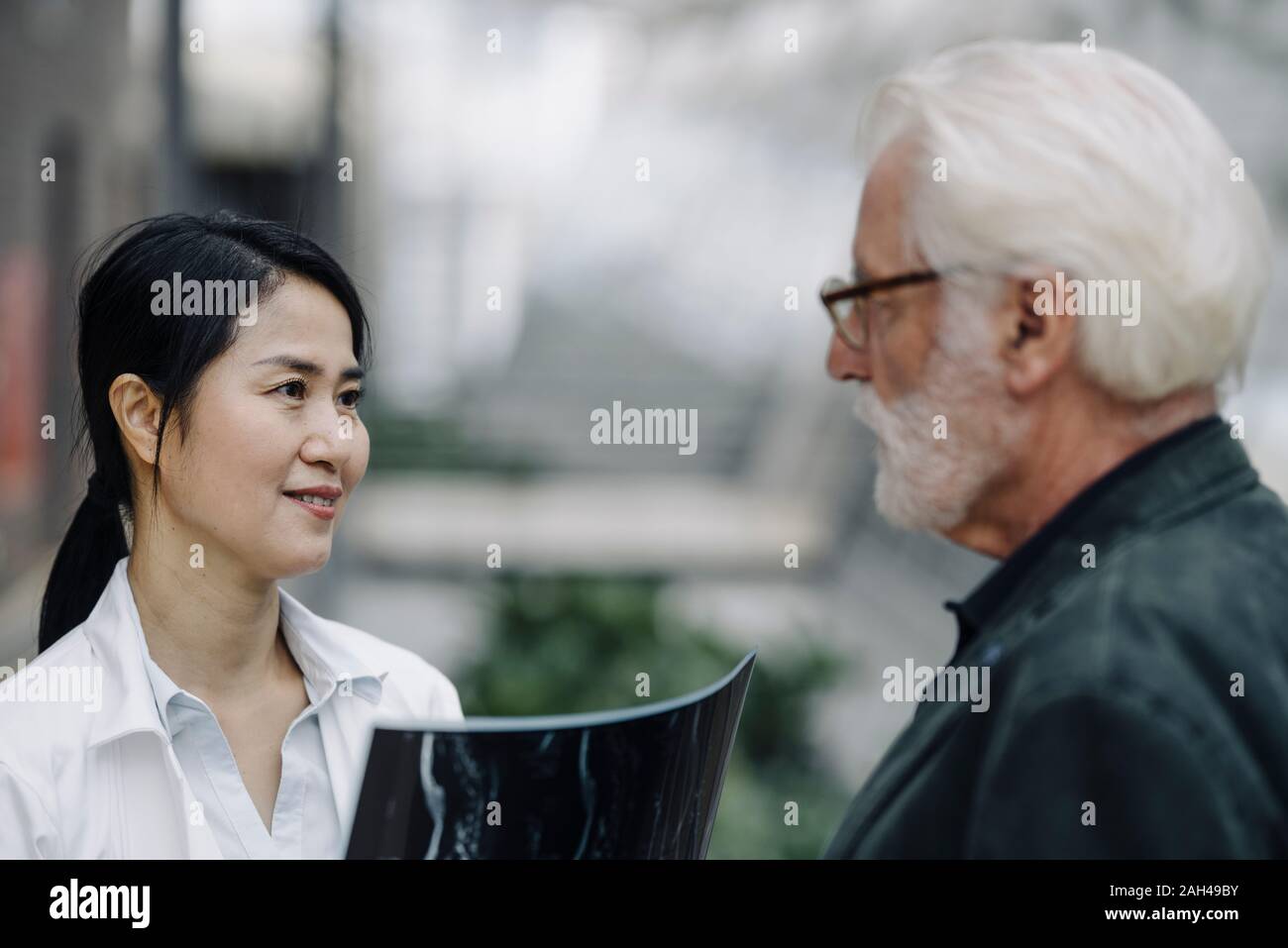 Smiling female doctor with x-ray and senior man talking Stock Photo