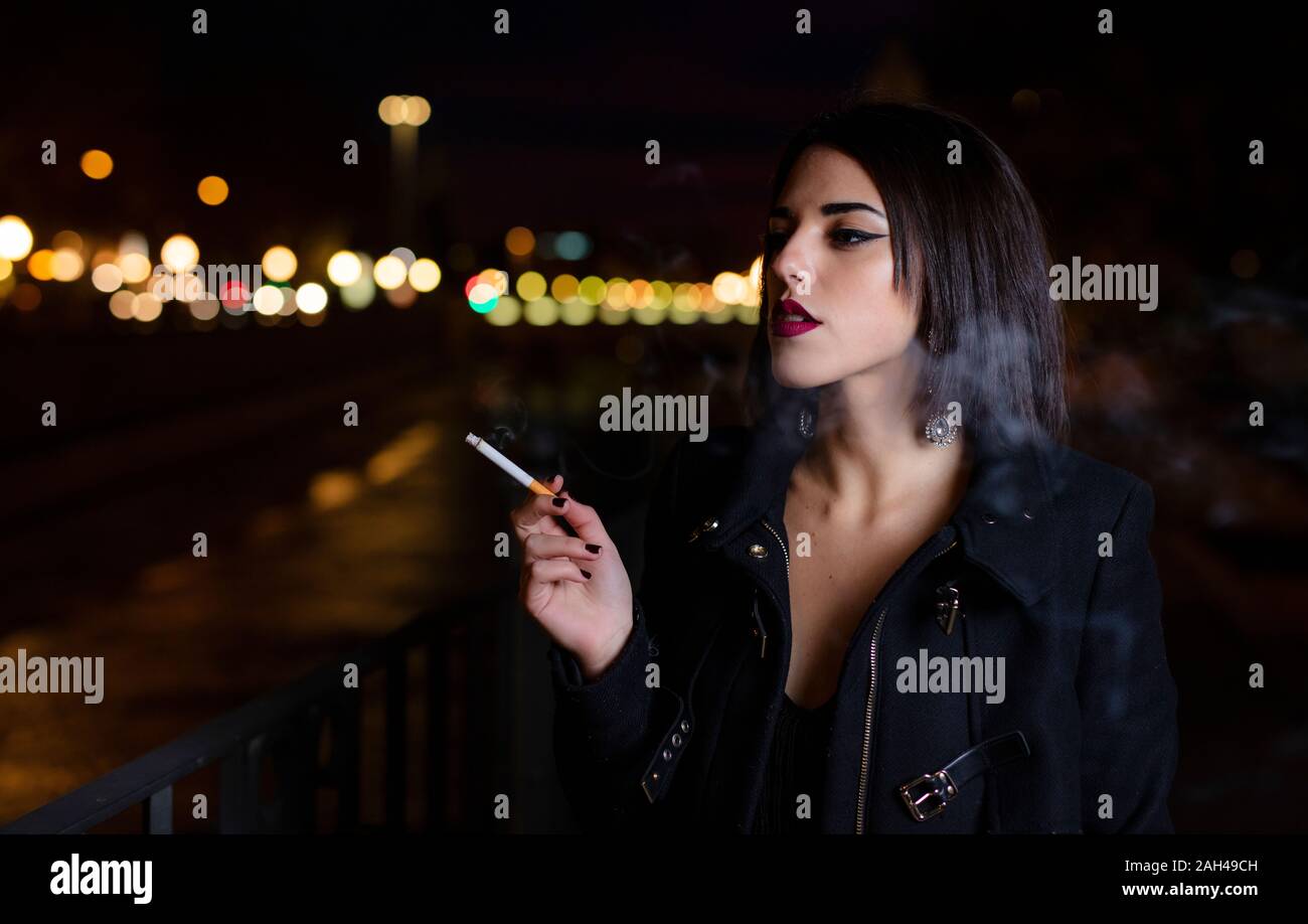 Portrait of smoking young woman at night Stock Photo