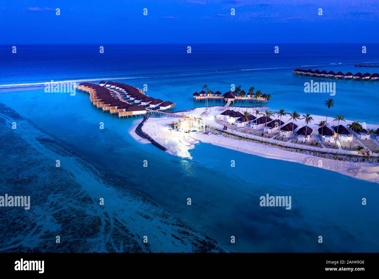 Maldives, Olhuveli, Aerial view of rows of beachside bungalows on South Male Atoll lagoon at dusk Stock Photo