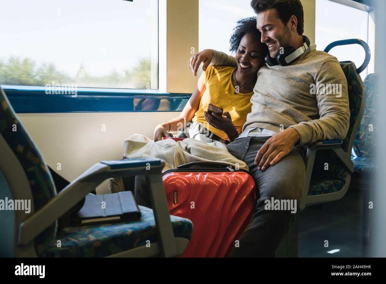 Young couple with smartphone relaxing in a train Stock Photo