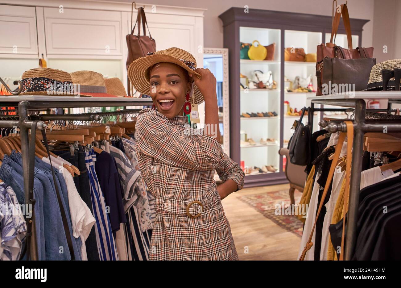 Young woman trying on a hat at a clothing shop Stock Photo