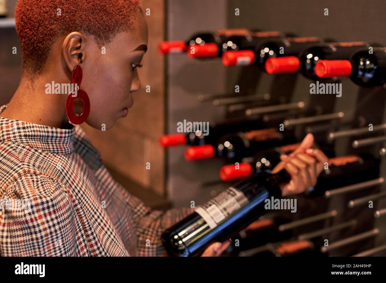 Young woman with short haircut choosing a wine in her cellar Stock Photo