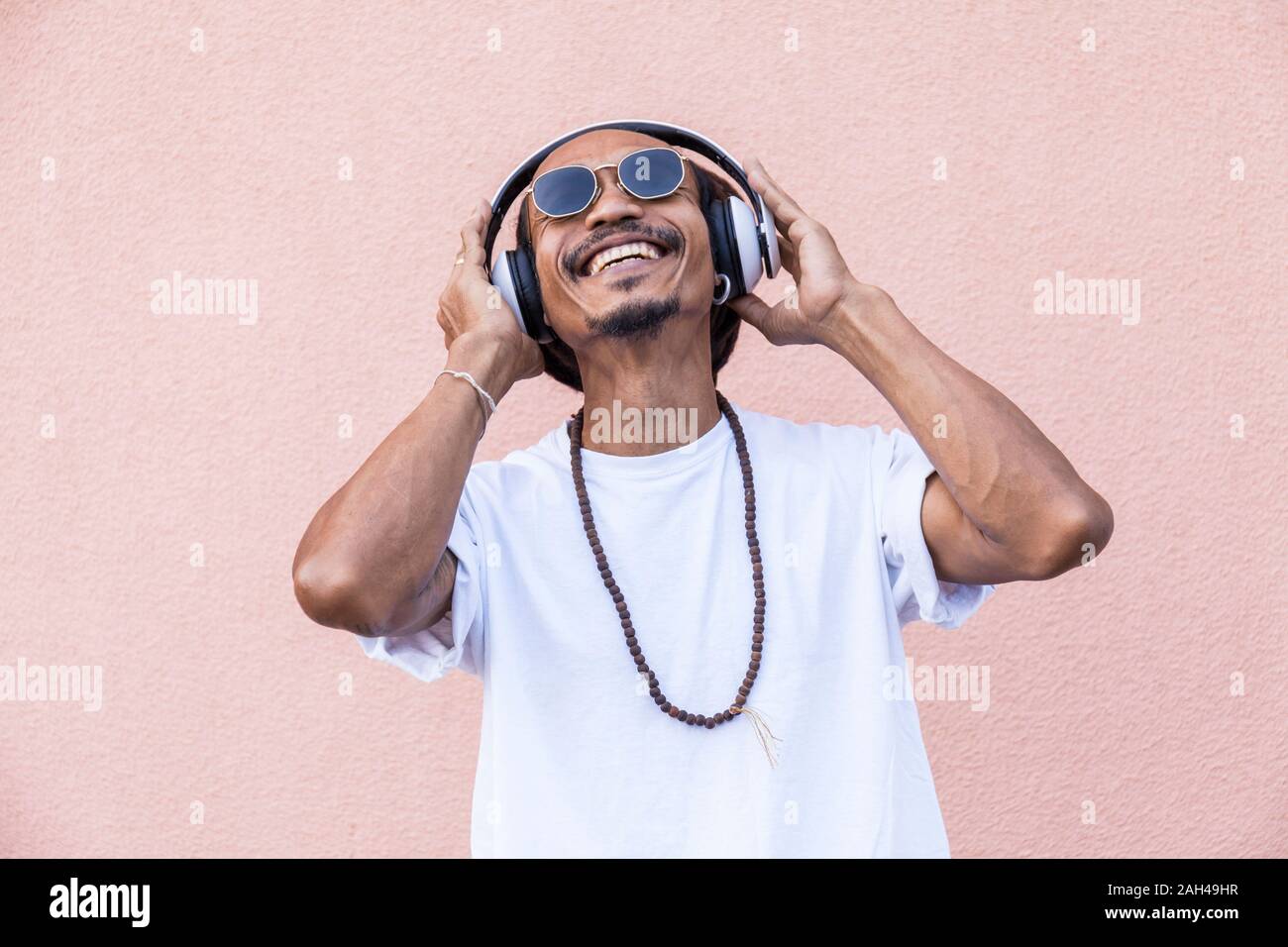Portrait of mature man with dreadlocks and headphones, listening music Stock Photo