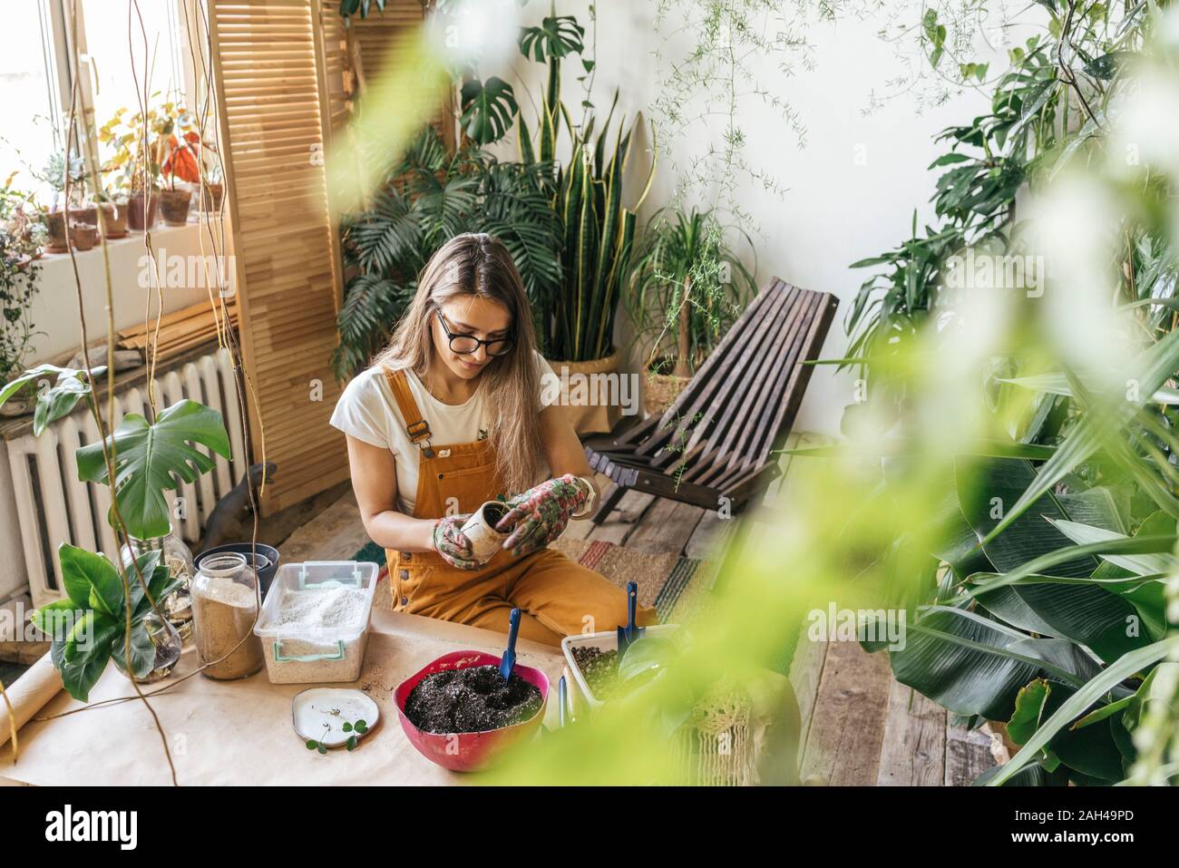 Young woman working with soil in a small gardening shop Stock Photo